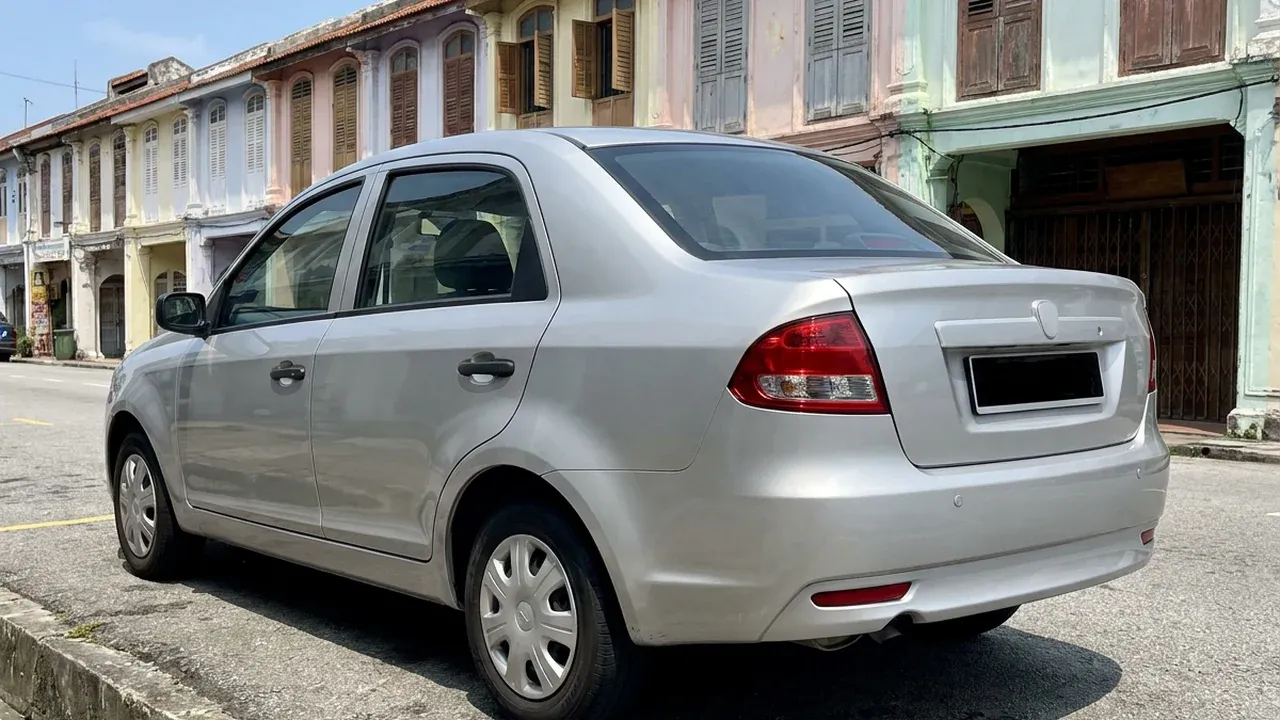 Rear view of an unbranded silver car parked in front of a row of colourful old Malaysian shophouses.