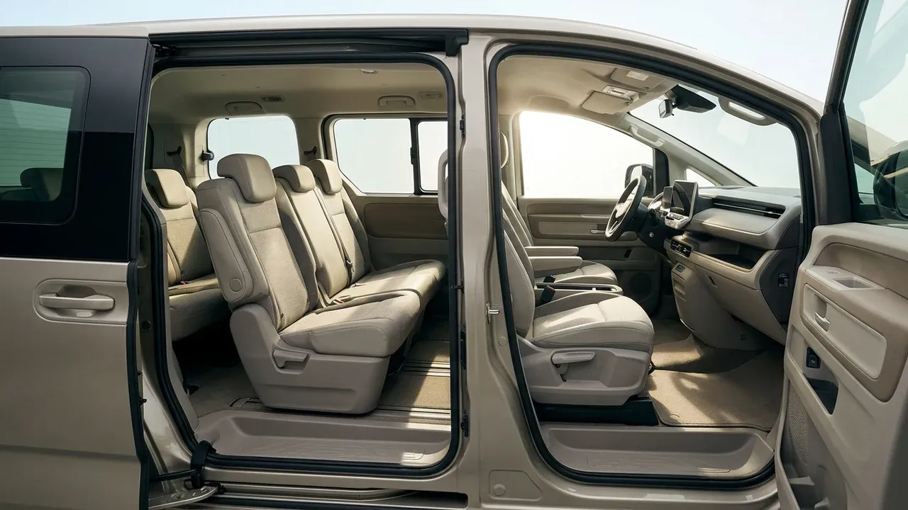 Interior of a clean modern seven-seater MPV seen through its open sliding door, showing three rows of seats in a bright cabin.