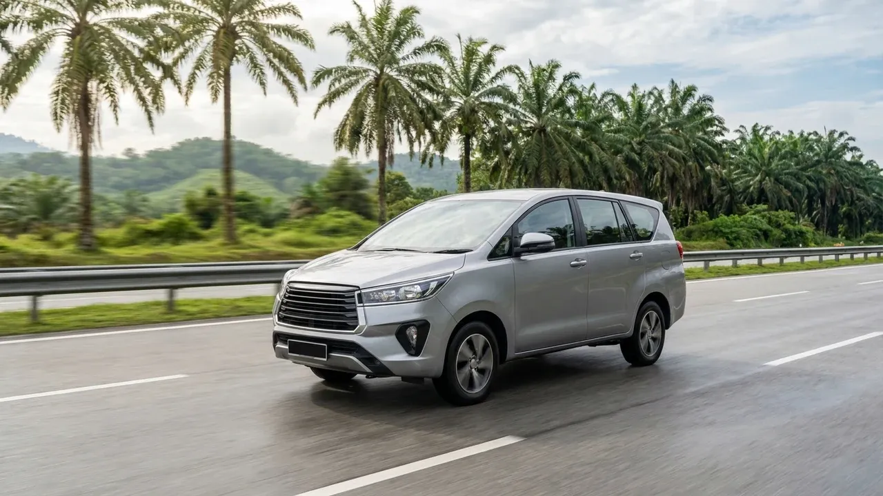 Unbranded silver MPV driving along a palm-lined Malaysian highway with soft green hills motion-blurred in the background.