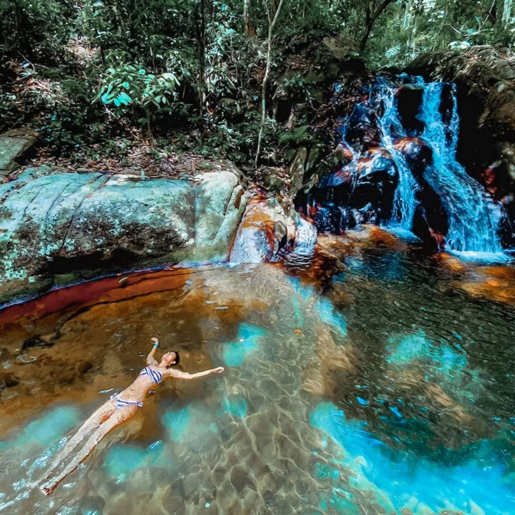 a woman floating under the asah waterfall, one of the popular things to do in the list of what to do in tioman